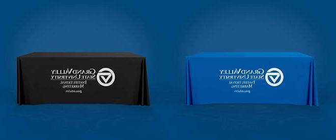 一张有蓝色桌布的桌子与一张有黑色桌布的桌子相邻. 两个球上都有一个白色的大峡谷大学营销标志.